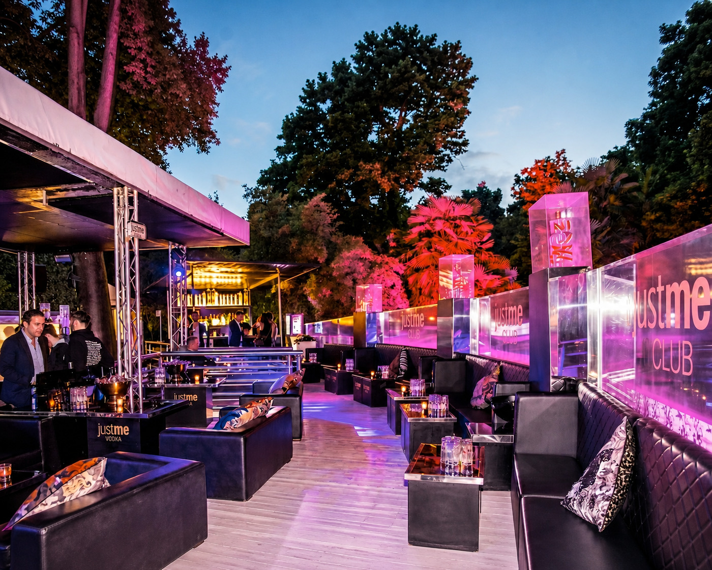Just Me Milan lounge with black sofas, low tables, pink lighting and venue signs